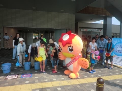 うながっぱに見守られて子どもたちがいっせいに打ち水。